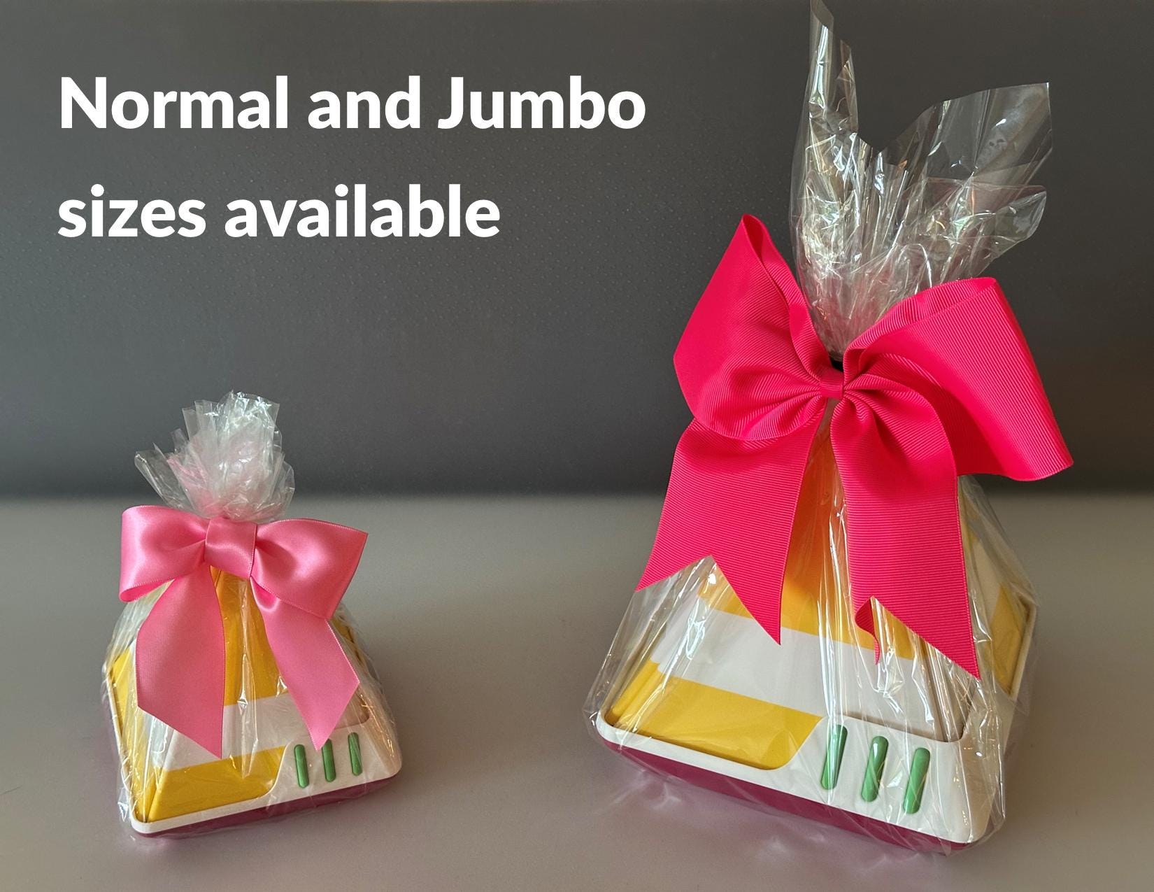 Two gift bags with pink bows, one normal and one jumbo, on a neutral background.